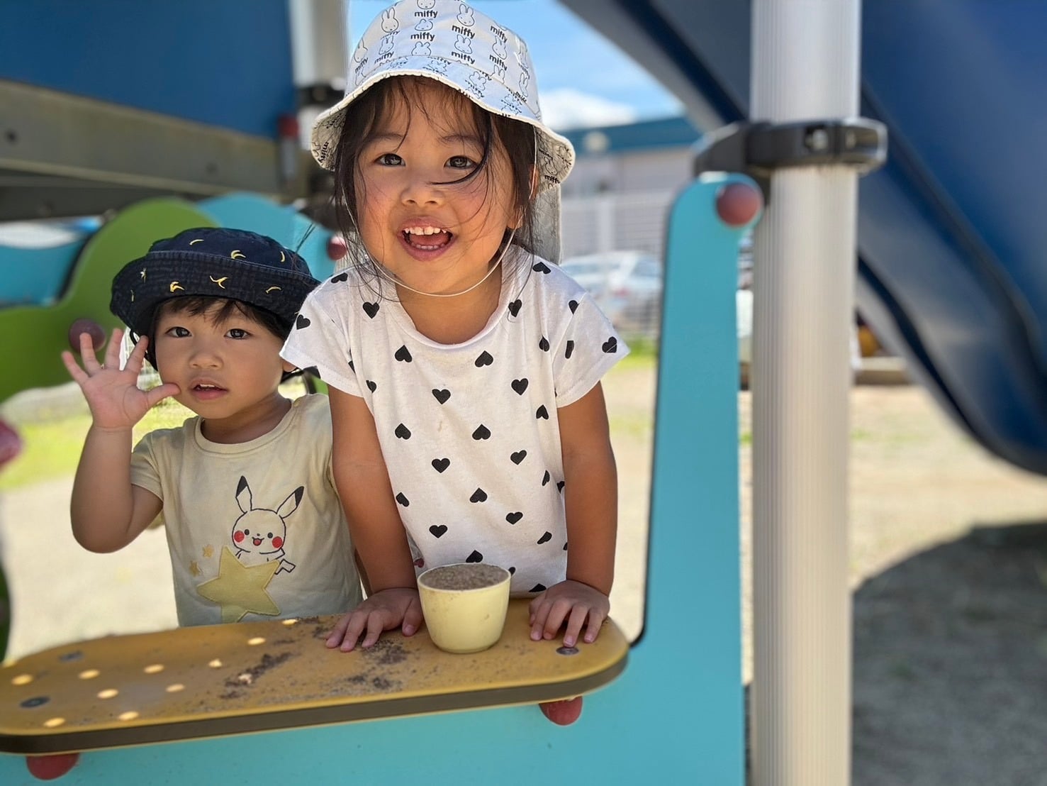園庭の遊具から笑顔を見せる子どもたち