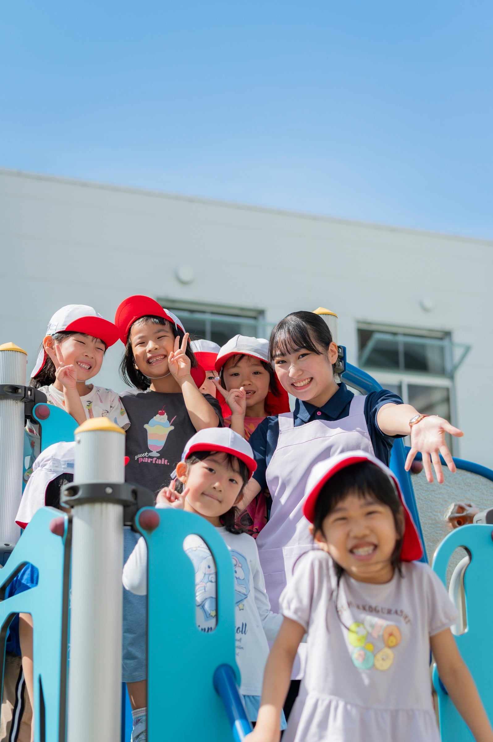 園庭で笑顔を見せる子どもたちと職員