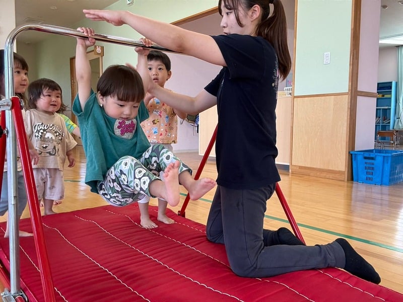 講師の補助を受けながら体操する子ども