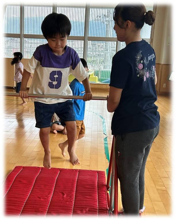 鉄棒に取り組む子どもと体操講師