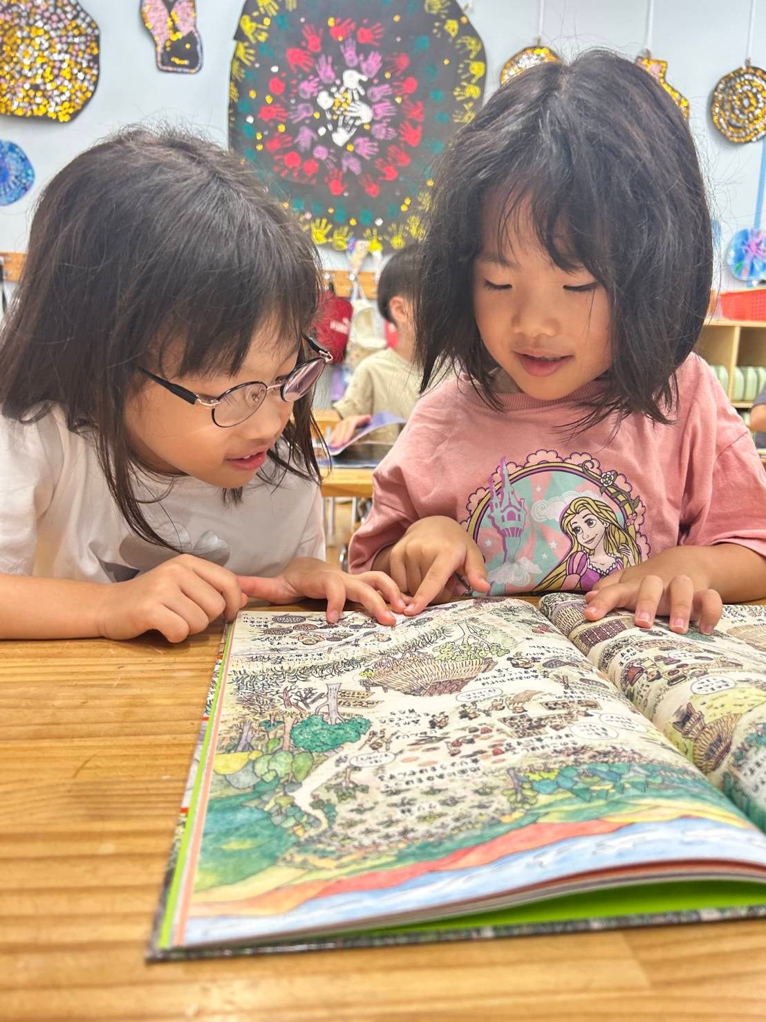 友だちと一緒に絵本を読む子どもたち