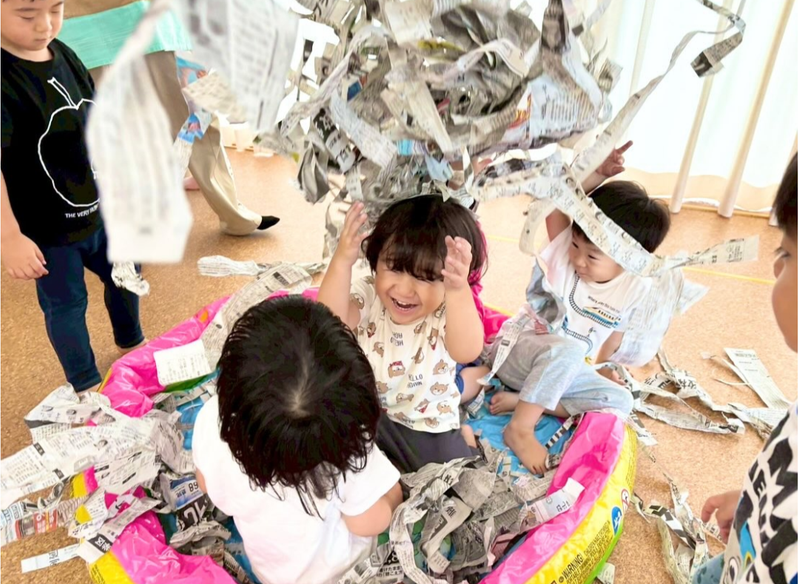 新聞紙を使って一緒に遊ぶ子どもたち