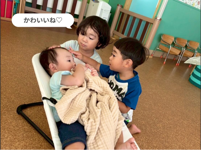 赤ちゃんを囲んで過ごす子どもたちと保育士